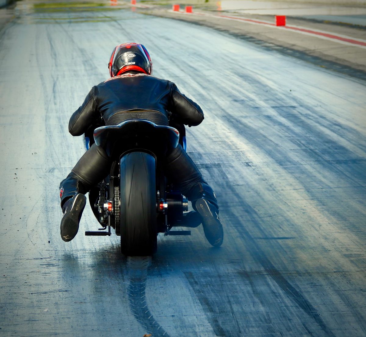 Back view of a motorcyclist speeding on a race track, showcasing skill and speed.